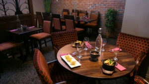 Cosy hotel restaurant with elegant tables, patterned chairs, delicious dishes, and a warm, inviting atmosphere.