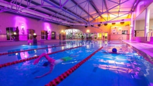 Guests enjoy a vibrant indoor pool with mood lighting, perfect for a relaxing swim at our luxurious hotel.