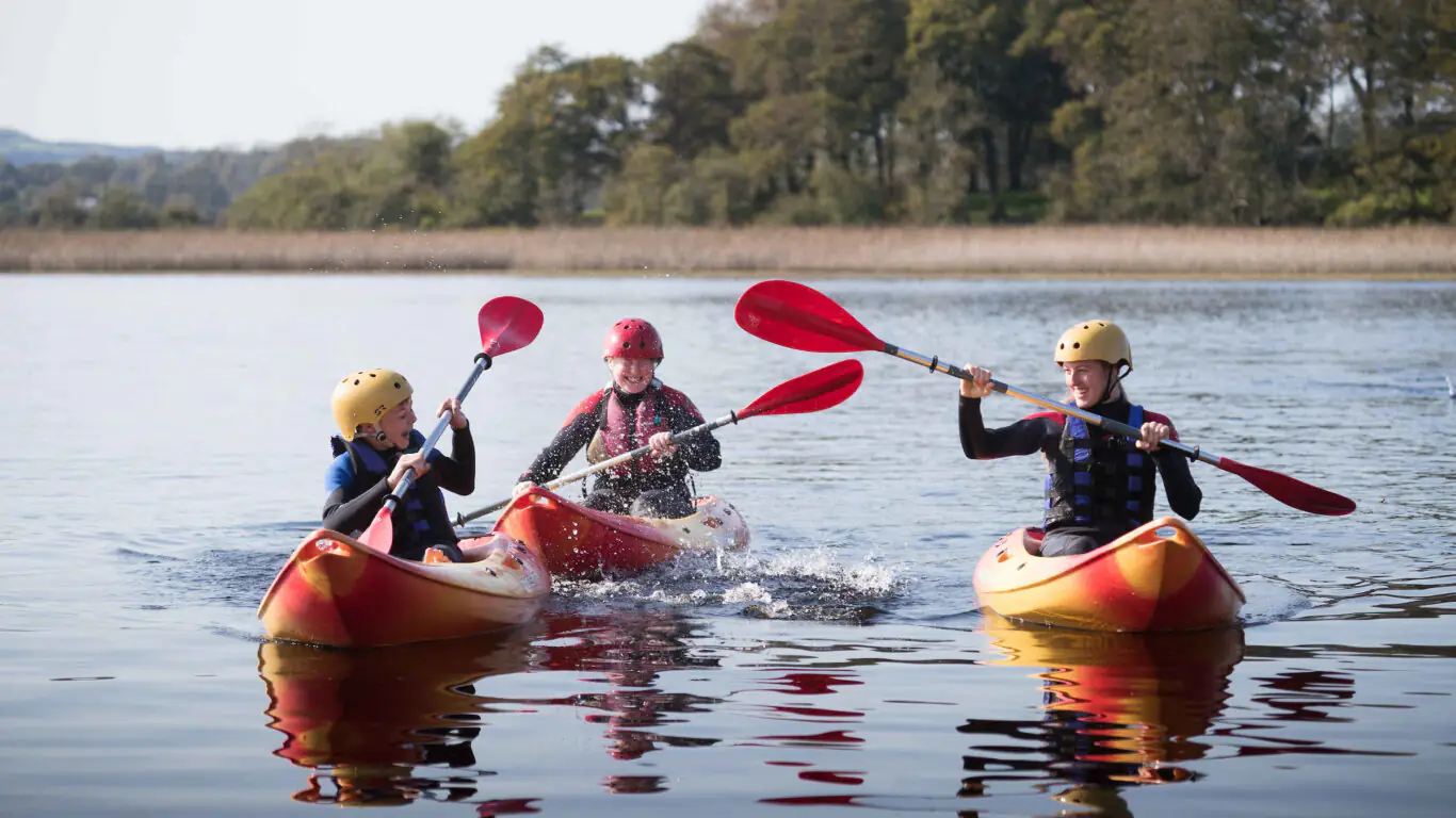 Guests kayaking on a serene lake with lush greenery, enjoying outdoor adventure and scenic views near the hotel.