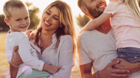 A cheerful family enjoys a sunny day in a hotel garden, with children smiling. Perfect for family-friendly stays.